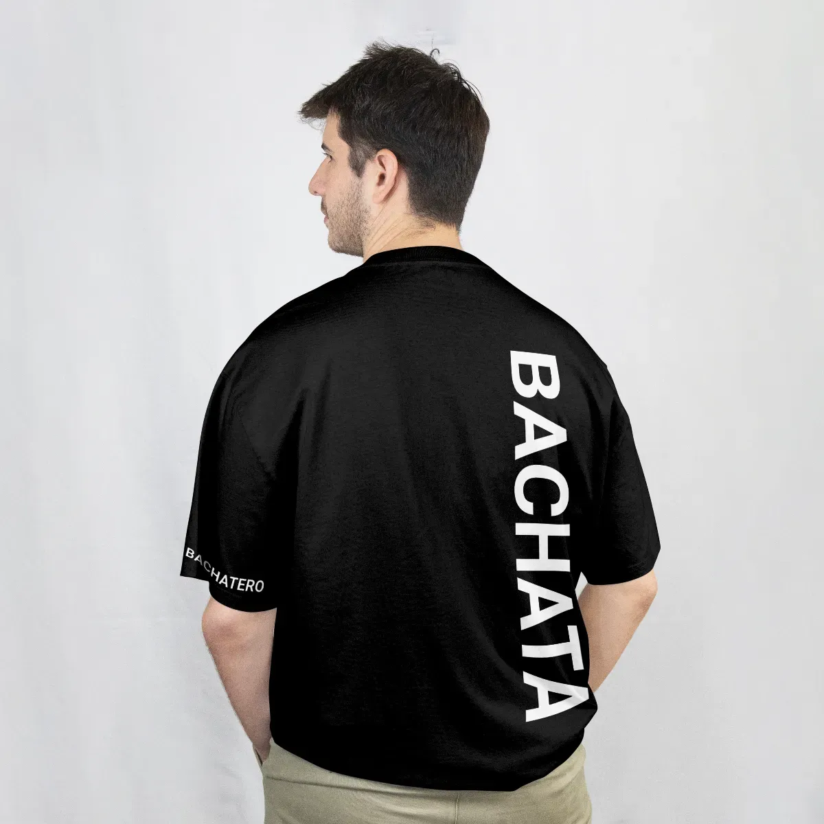 Playera negra de espalda con la palabra Bachata en vertical, en blanco, sobre el hombro y la manga